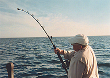 Man fishing with rod bent over, fish on it