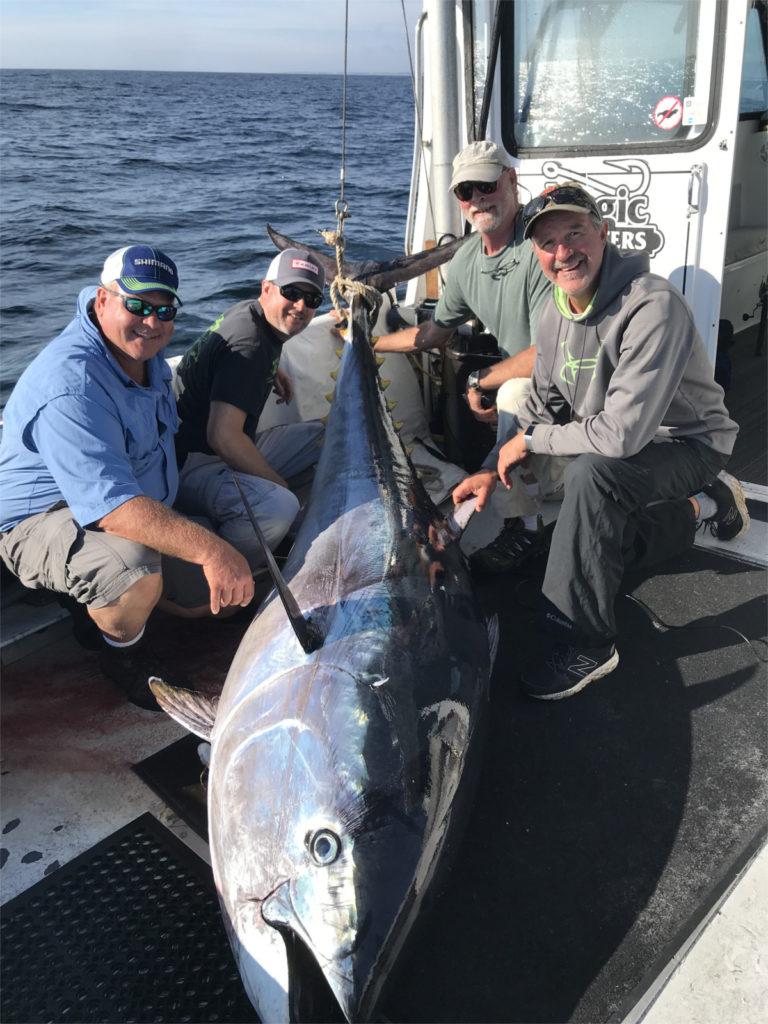 Four guys in caps clustered around 600 pound bluefin tuna on board F/V Magic