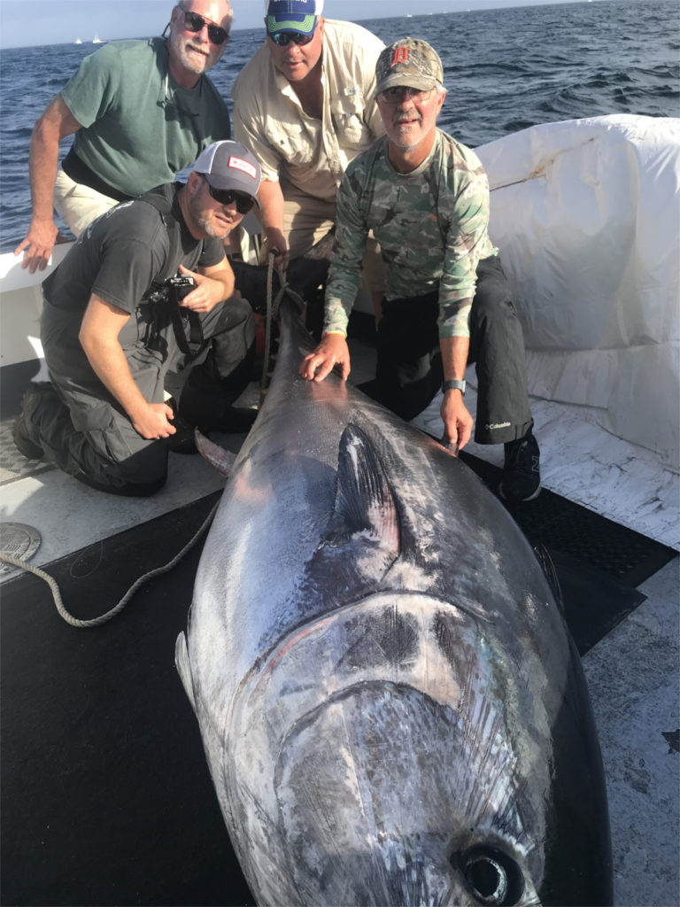 Four guys clustered around 700 pound bluefin tuna on board F/V Magic