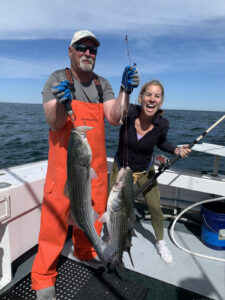 Captain Mike and woman each holding large stripers