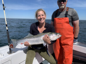 Smiling woman holding huge striped bass