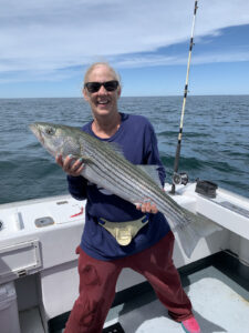 Smiling woman holding huge striped bass