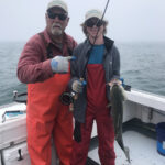 Captain Mike and young man holding a striped bass