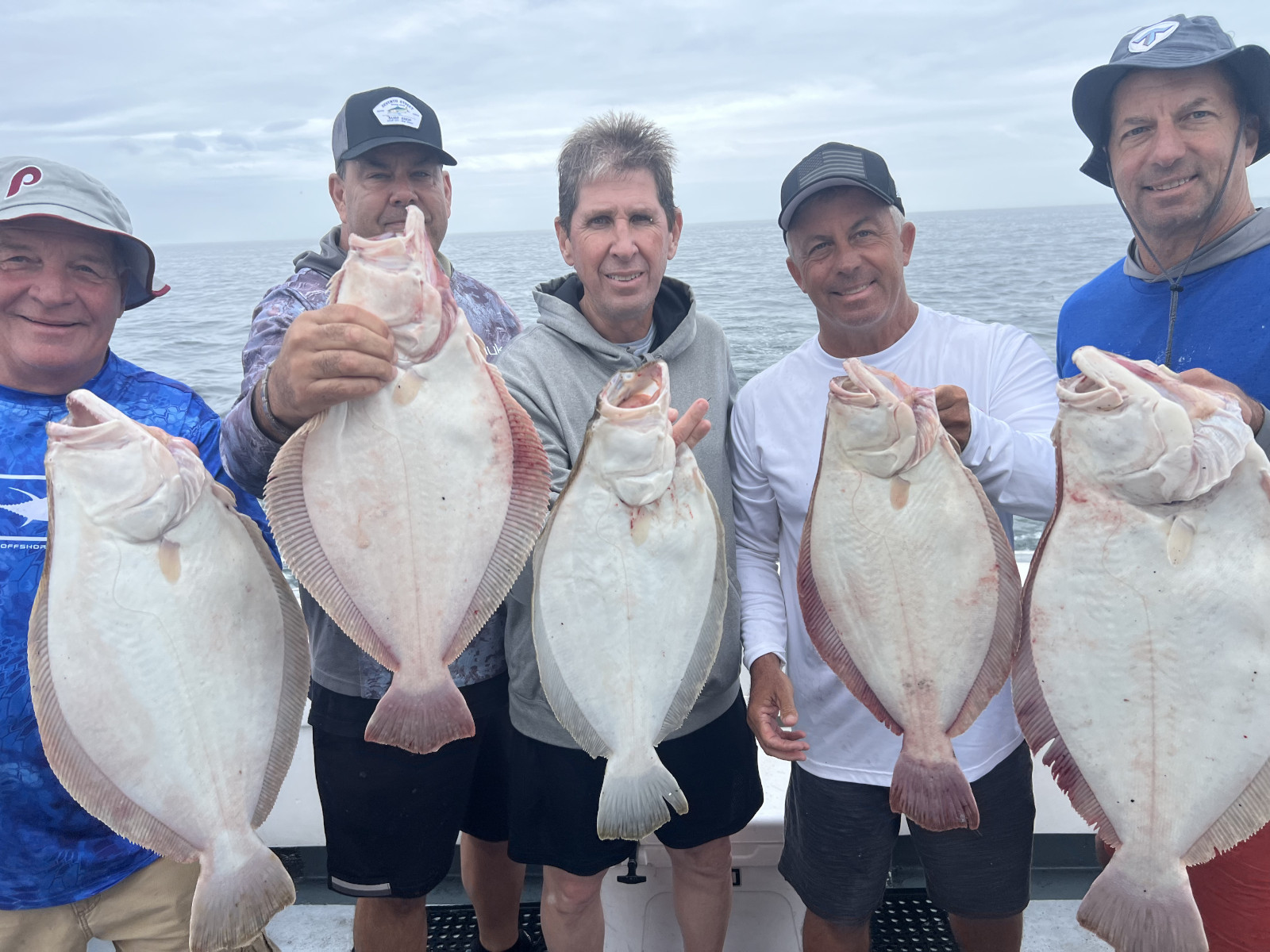 Five people standing on the Magic, each holding a summer flounder caught on the fishing trip