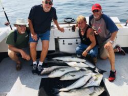 Four guys with a deck of many striped bass (about ten)