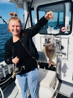 Very proud young girl holding porgy on fishing line - first fish she ever caught