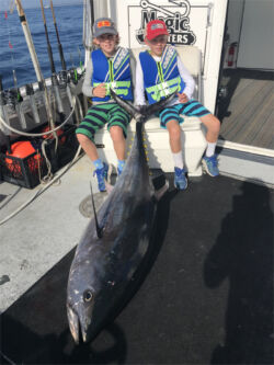 Twin boys sitting with large bluefin tuna on deck of F/V Magic