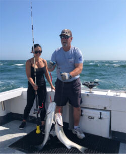 Two striped bass caught on one fishing rig, woman and captain happy