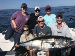 Six people holding a tuna proudly