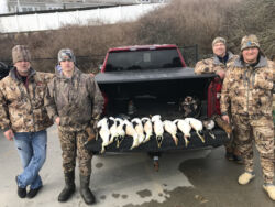 Four men in camouflage gear with sea ducks