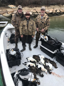 Three men in camouflage gear with sea ducks