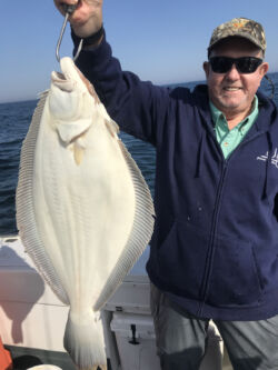 Man holding up huge fluke caught on fishing trip