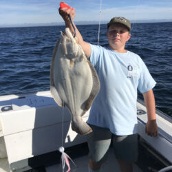 Boy on deck of Magic Charters holding up fluke