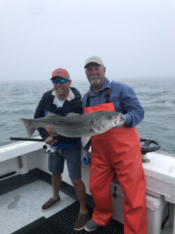 Charter customer and Captain Mike holding a very large striped bass