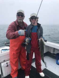 Captain Mike and young man holding a striped bass