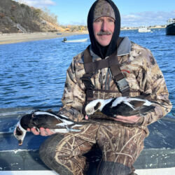 Two long-tailed ducks held by a hunter